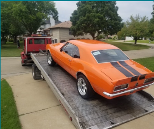 Classic muscle car secured on flatbed tow truck